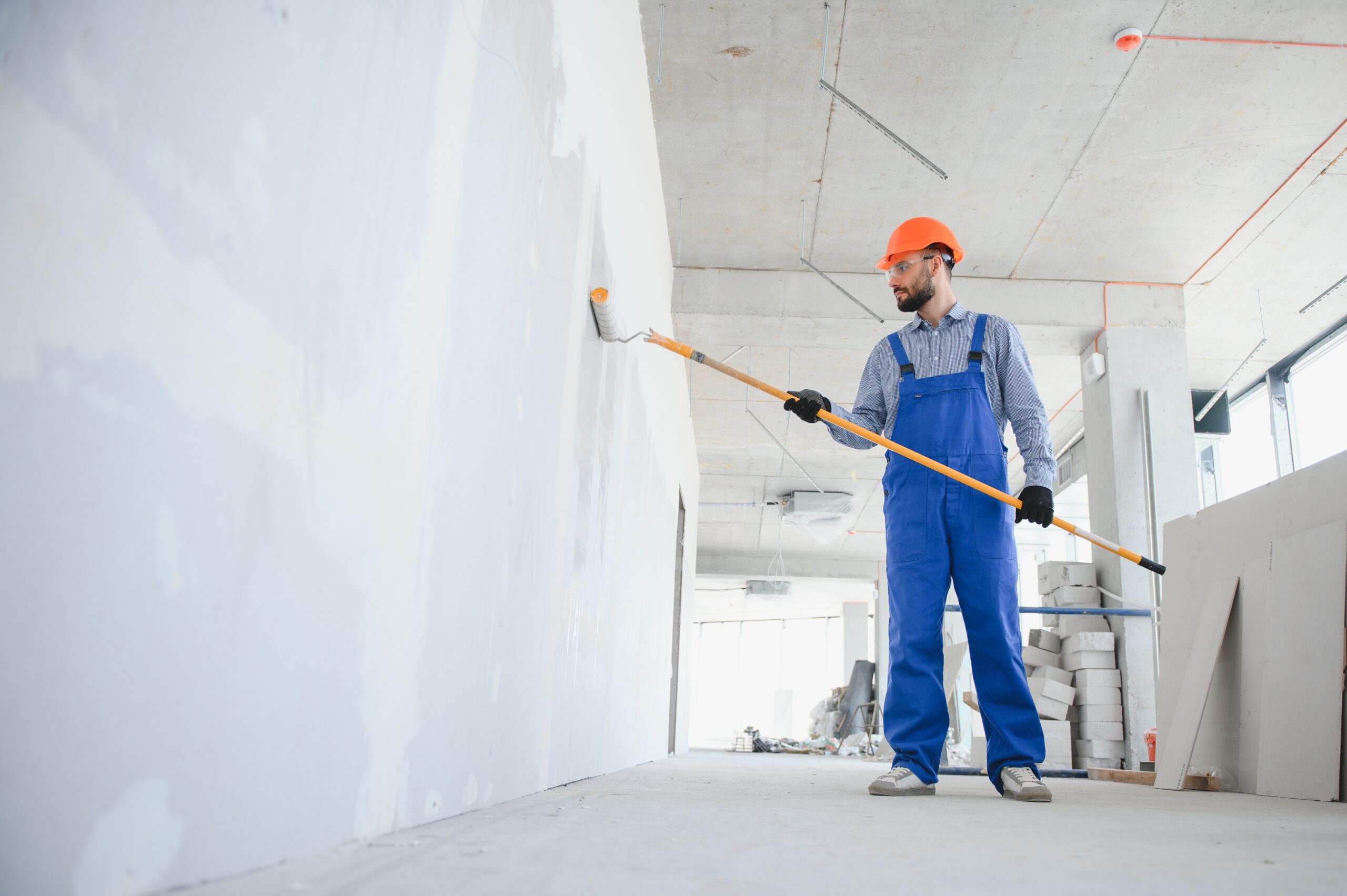 painter man painting the wall, with paint roller.