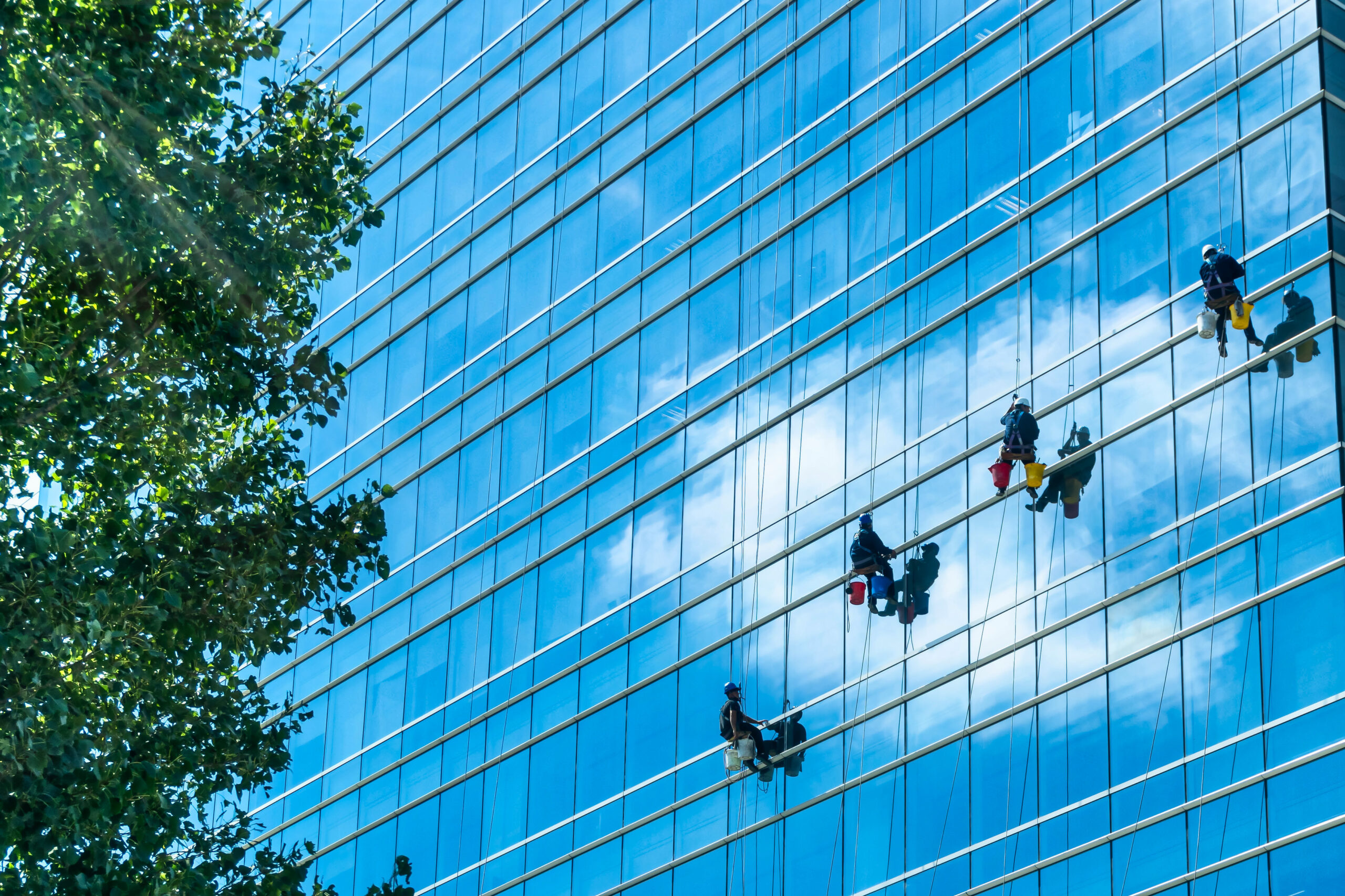 A group of cleaners in safety harness cleaning glass windows of a modern high-rise building in Buenos Aires, Argentina