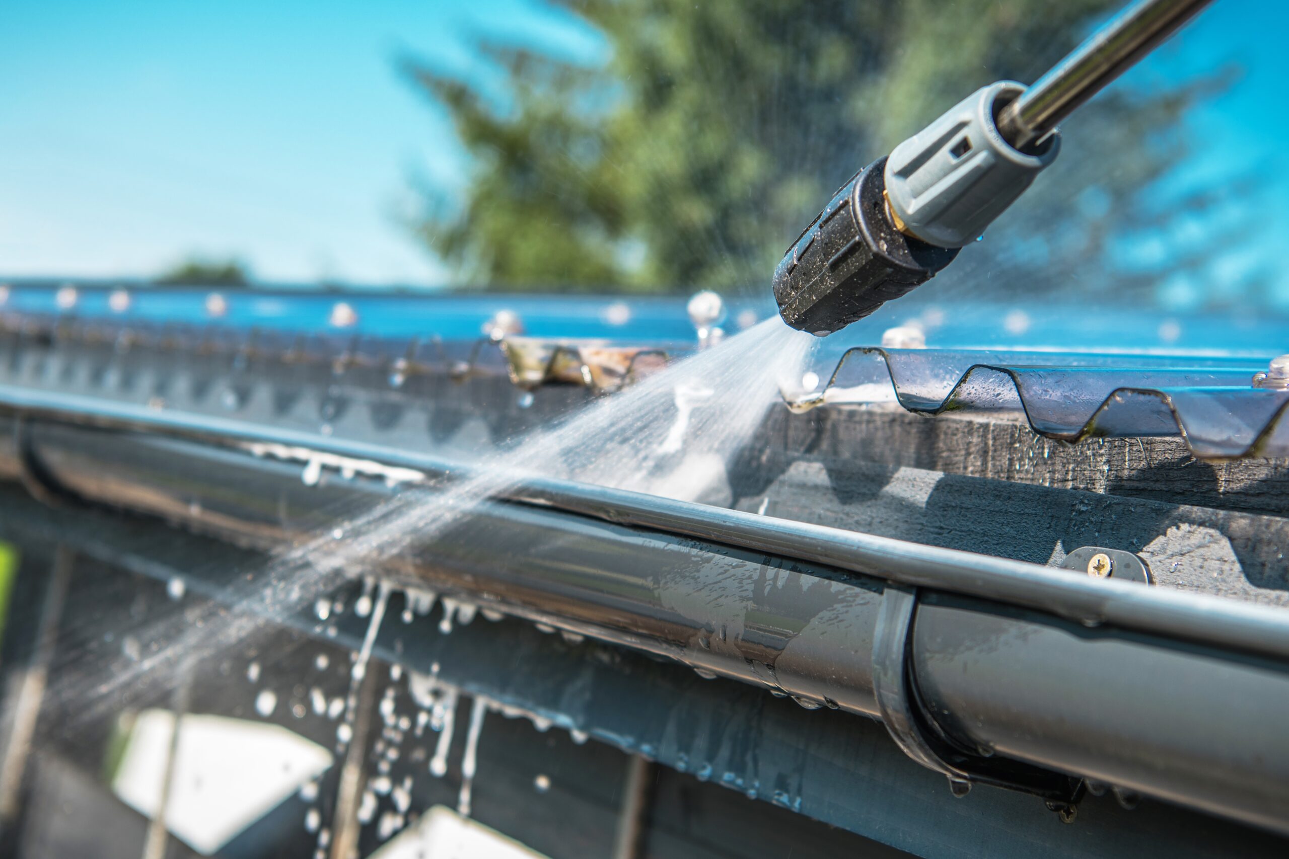 Spring Rain Gutters Cleaning Using Pressure Washer. Closeup Photo.