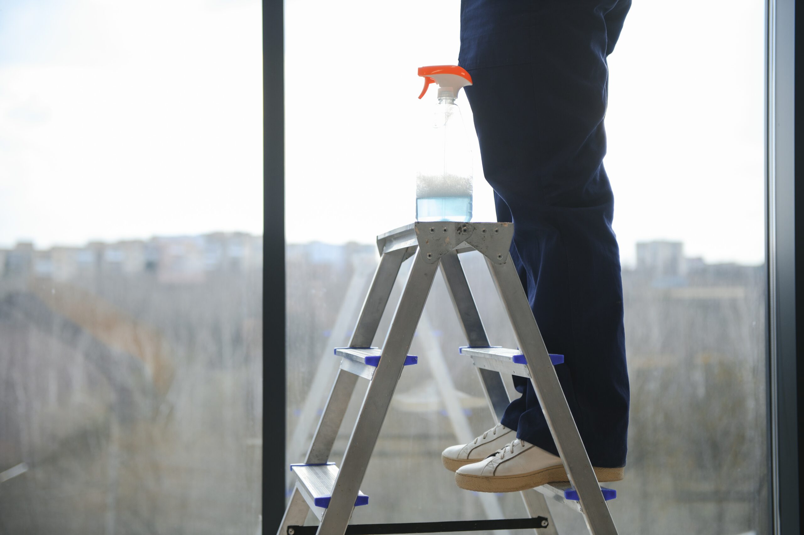 An employee of a professional cleaning service washes the glass of the windows of the building. Showcase cleaning for shops and businesses