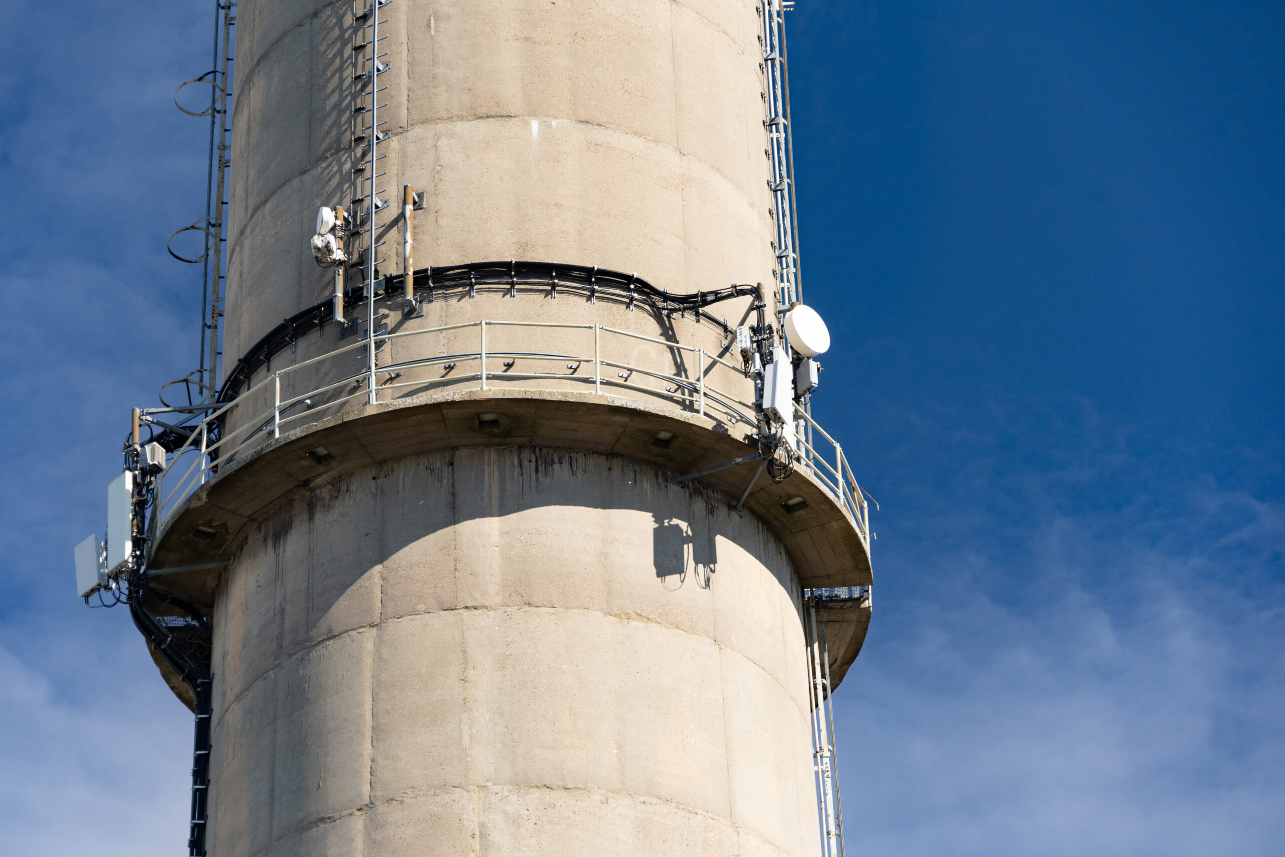 A low angle shot of a textile factory chimney on a sunny day with the blue cloudy sky in the background