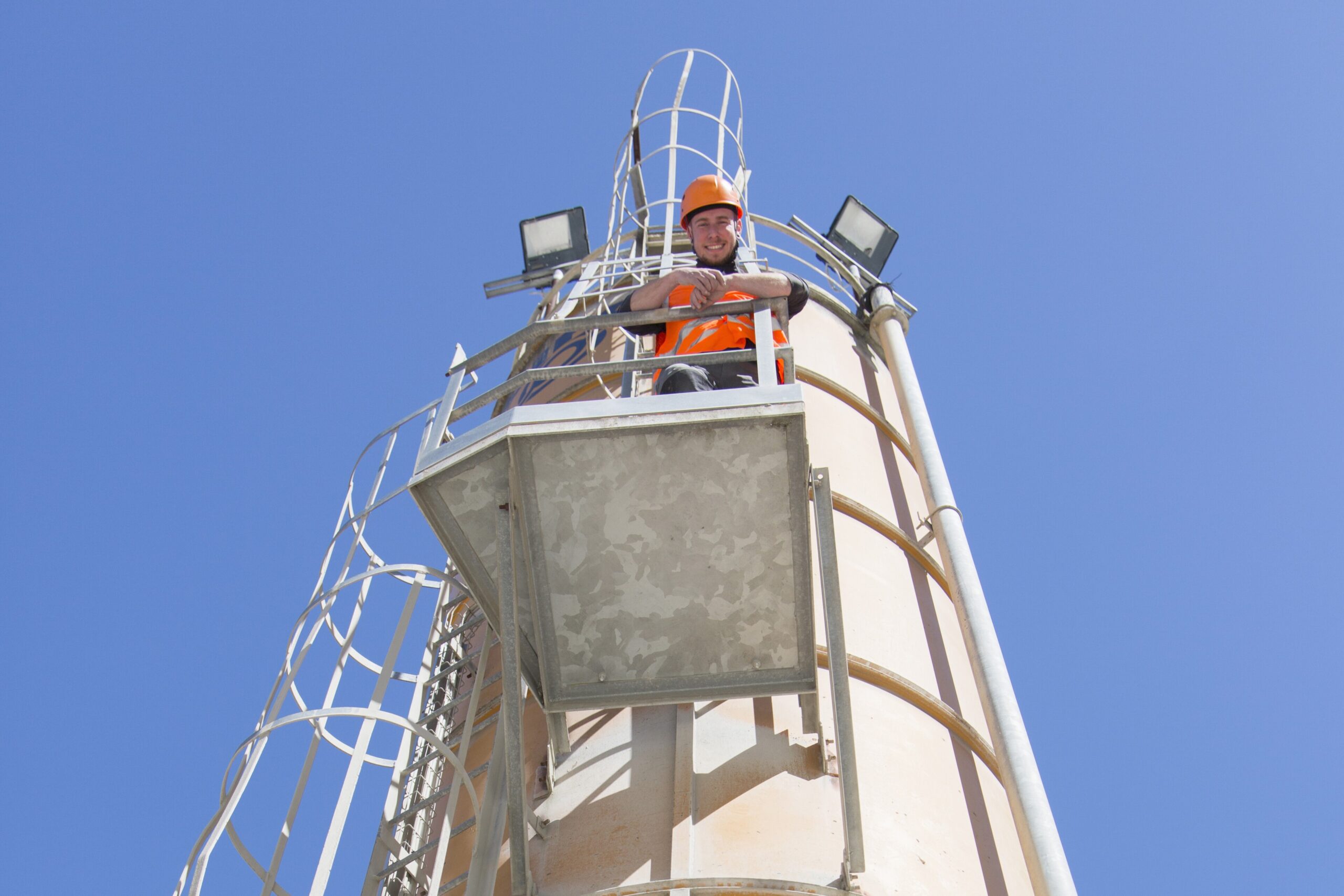 Low angle portrait of worker on smoke stack viewing platform